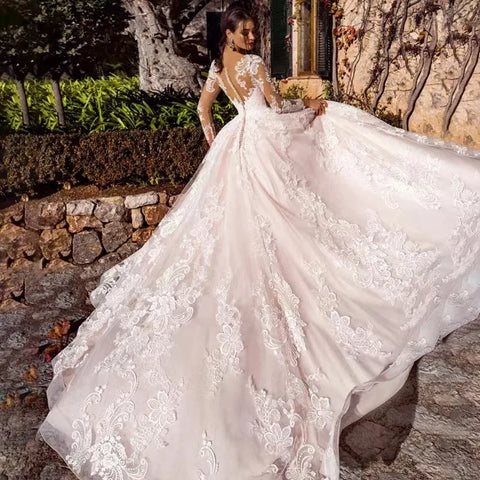 Vestido de novia de corte princesa, elegante, de manga larga, con espalda ilusión y escote redondo.