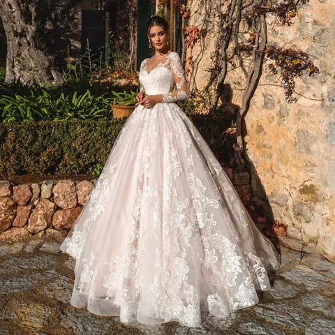 Vestido de novia de corte princesa, elegante, de manga larga, con espalda ilusión y escote redondo.