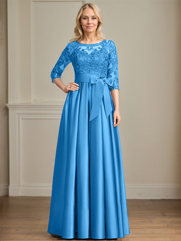 Robe de mariée longue en satin et dentelle, coupe trapèze, décolleté illusion, ornée d'un nœud à sequins. 