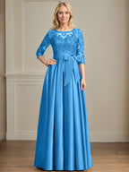 Robe de mariée longue en satin et dentelle, coupe trapèze, décolleté illusion, ornée d'un nœud à sequins. 