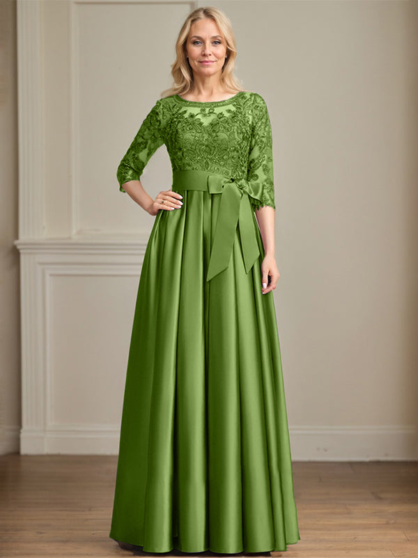 Robe de mariée longue en satin et dentelle, coupe trapèze, décolleté illusion, ornée d'un nœud à sequins. 