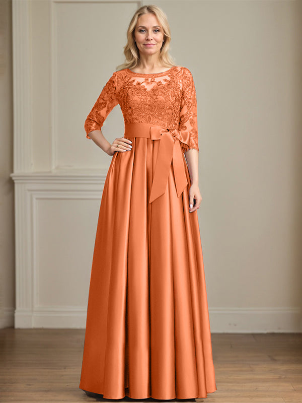 Robe de mariée longue en satin et dentelle, coupe trapèze, décolleté illusion, ornée d'un nœud à sequins. 