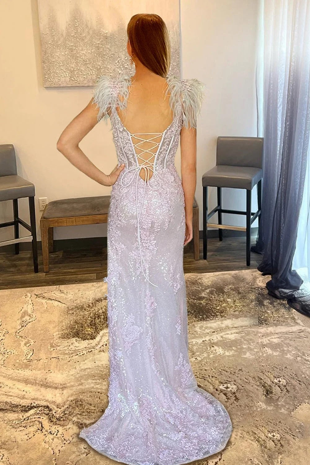 Vestido de fiesta sirena con apliques rosas y abertura lateral, adornado con plumas.