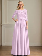 Robe de mariée longue en satin et dentelle, coupe trapèze, décolleté illusion, ornée d'un nœud à sequins. 