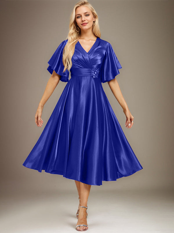 Vestido de novia de satén elástico, corte en A, escote en V, largo hasta la rodilla, con cuentas y pliegues. 