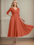 Vestido de corte A, escote en V, largo hasta la rodilla, de gasa, encaje, con lentejuelas y pedrería para la madre de la novia. 