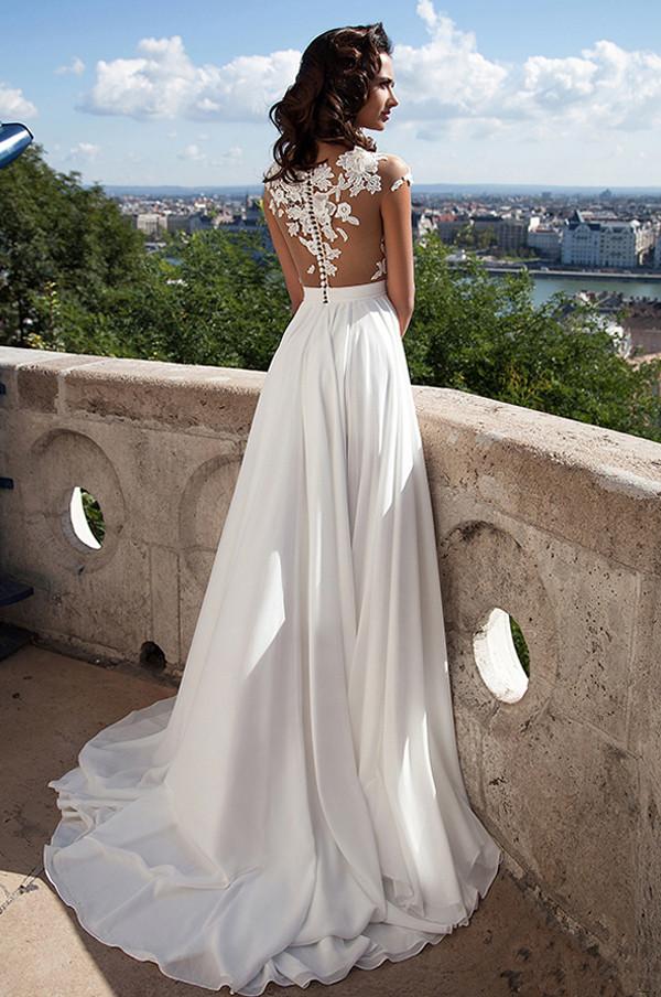 Vestido de novia blanco de encaje con corte en A, abertura frontal y apliques.