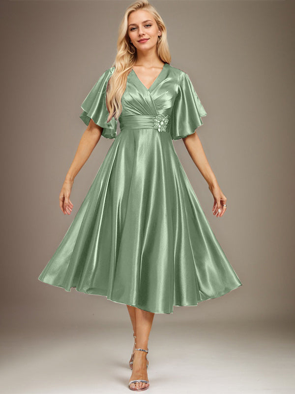 Vestido de novia de satén elástico, corte en A, escote en V, largo hasta la rodilla, con cuentas y pliegues. 