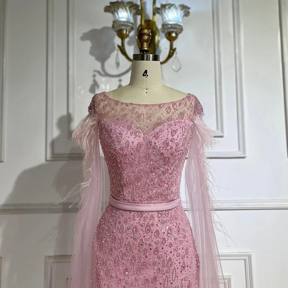 Vestido de noche de sirena con mangas tipo capa rosa estilo Dubai, falda lateral, plumas y cuentas, modelo LA72701 (2025) 