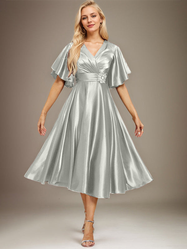 Vestido de novia de satén elástico, corte en A, escote en V, largo hasta la rodilla, con cuentas y pliegues. 