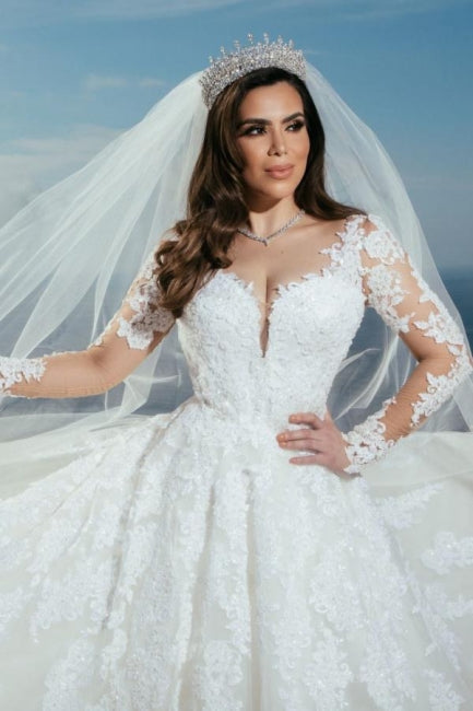 Robe de mariée longue en tulle, coupe trapèze, décolleté en cœur et ornée d'appliques.