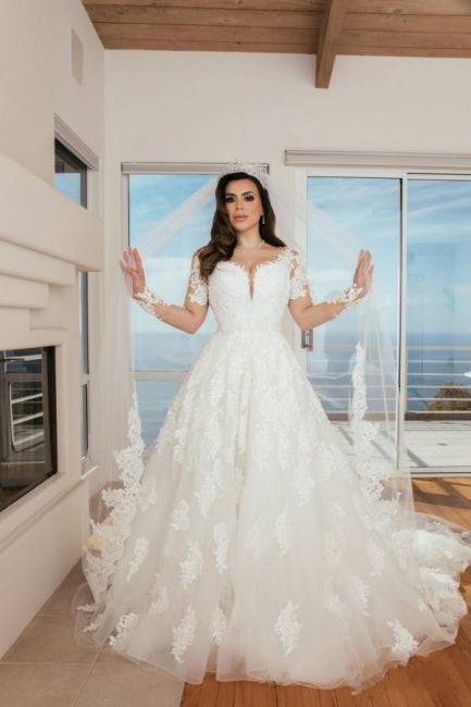 Robe de mariée longue en tulle, coupe trapèze, décolleté en cœur et ornée d'appliques.