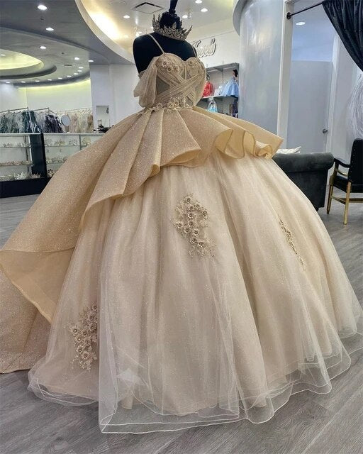 Vestido de quinceañera estilo princesa, color champán brillante, con elegantes tirantes y apliques. Modelo Y4150.