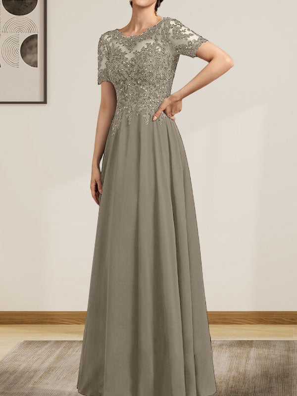Robe de mariée longue en mousseline de soie et dentelle, coupe trapèze, décolleté illusion, ornée de sequins et de perles.