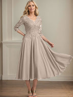 Vestido de corte A, escote en V, largo hasta la rodilla, de gasa, encaje, con lentejuelas y pedrería para la madre de la novia. 