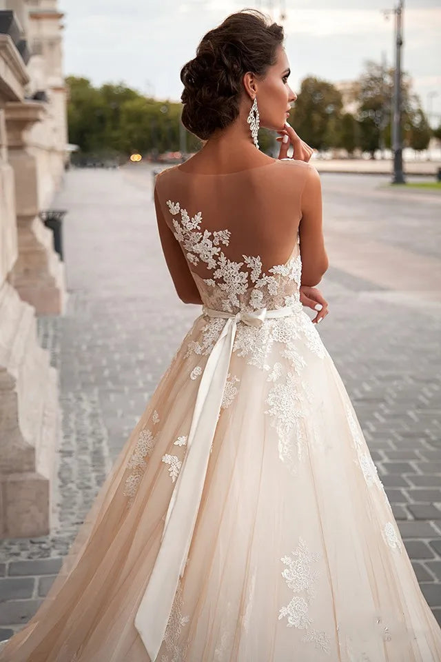 Vestido de novia transparente color champán con cinturón de perlas extraíble, sin mangas, espalda descubierta y encaje (Serie 2023). 