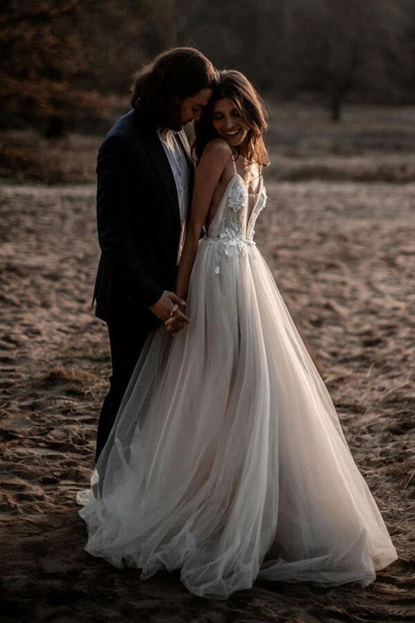 Robe de mariée en tulle, coupe trapèze, décolleté plongeant en V, dos nu et fines bretelles spaghetti