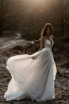 Robe de mariée en tulle, coupe trapèze, décolleté plongeant en V, dos nu et fines bretelles spaghetti