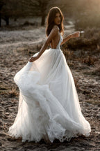 Robe de mariée en tulle, coupe trapèze, décolleté plongeant en V, dos nu et fines bretelles spaghetti