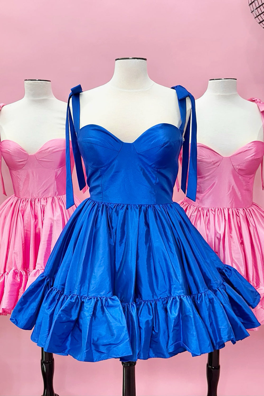Robe de bal courte rose fuchsia à fines bretelles spaghetti et coupe princesse, ornée de fronces.