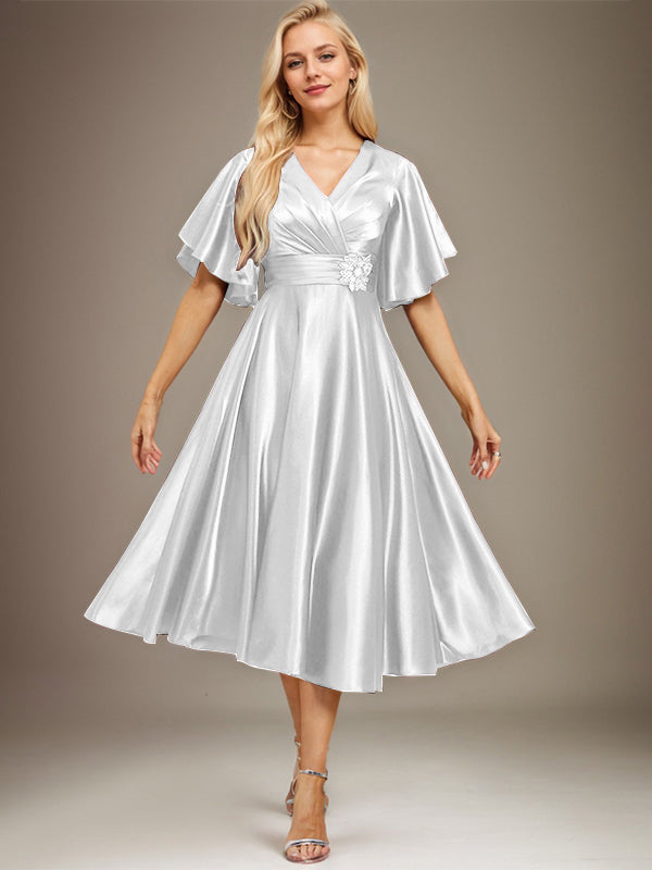Vestido de novia de satén elástico, corte en A, escote en V, largo hasta la rodilla, con cuentas y pliegues. 