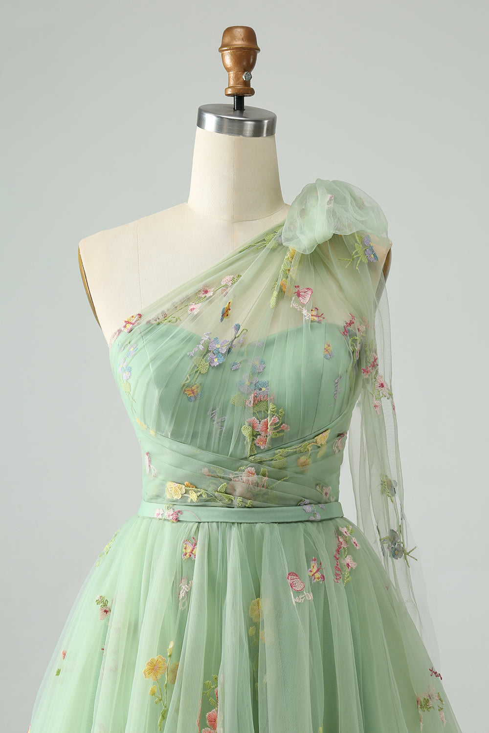 Robe de bal asymétrique gris-bleu en tulle, coupe trapèze, ornée de broderies florales et d'une épaule dénudée. Broderie florale.