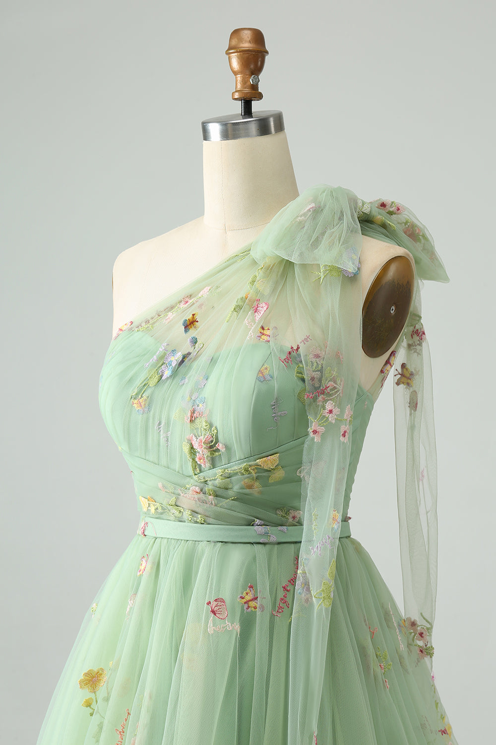 Robe de bal asymétrique gris-bleu en tulle, coupe trapèze, ornée de broderies florales et d'une épaule dénudée. Broderie florale.