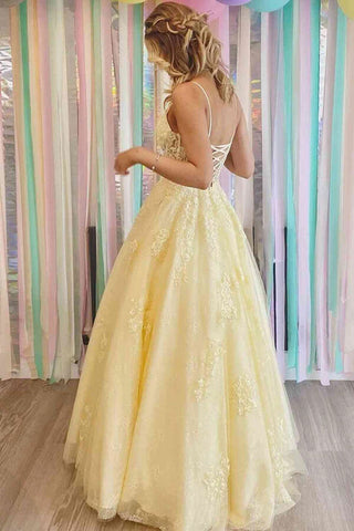 Robe de bal longue en tulle jaune, coupe trapèze, col en V, ornée d'appliques en dentelle.