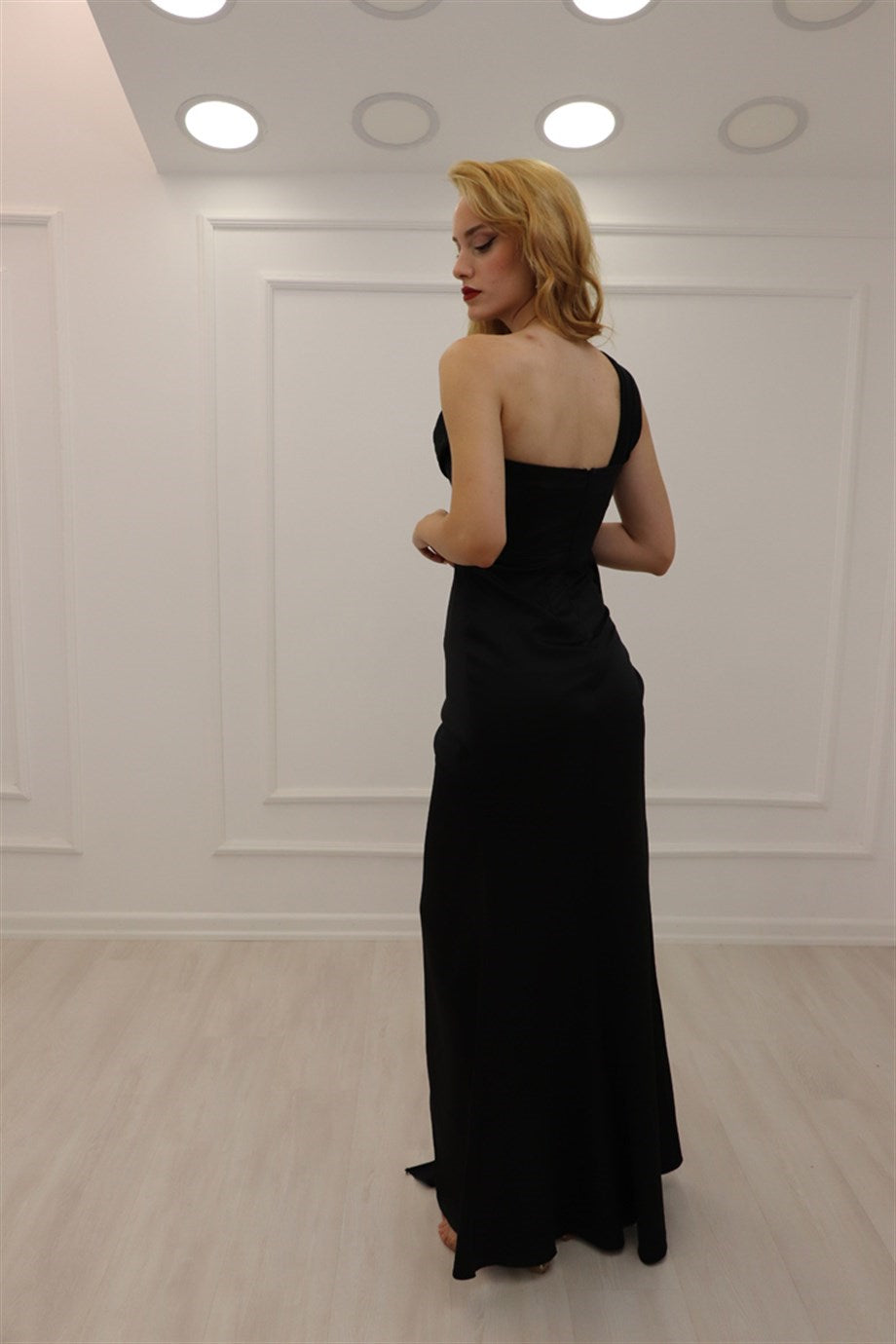 Vestido de fiesta negro de corte A, asimétrico, sin mangas, con lentejuelas y abertura.