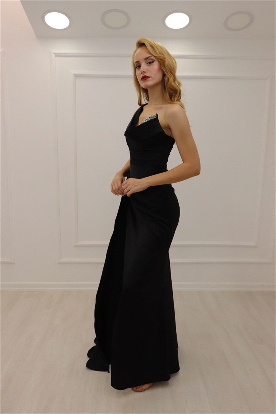 Vestido de fiesta negro de corte A, asimétrico, sin mangas, con lentejuelas y abertura.