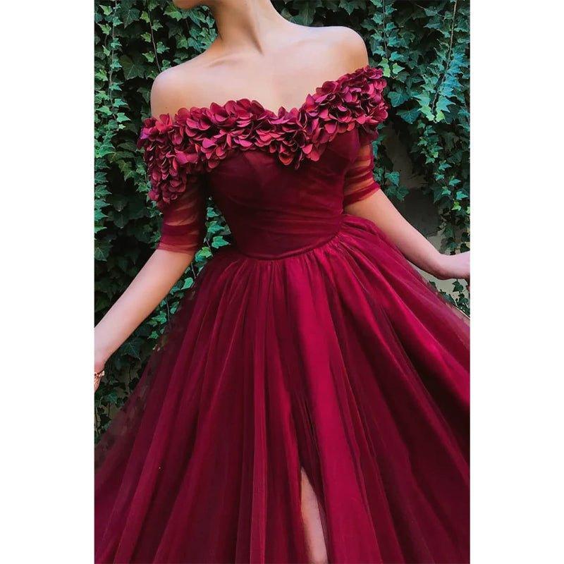 Vestido largo de noche formal, corte en A, de tul burdeos, con hombros descubiertos, apliques y abertura. 