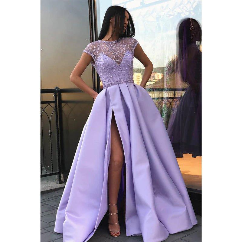 Vestido largo de fiesta de corte A, color lila, con escote ilusión de satén, encaje, pedrería, abertura alta y bolsillos. 
