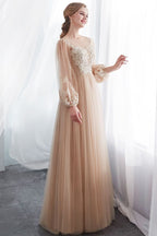 Vestido de noche de tul color champán con apliques, manga larga y corte en A