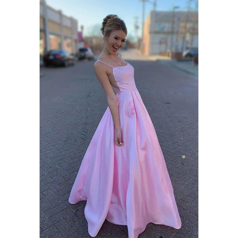 Vestido largo de fiesta rosa satinado de corte evasé con tirantes finos, escote redondo y bolsillos. 