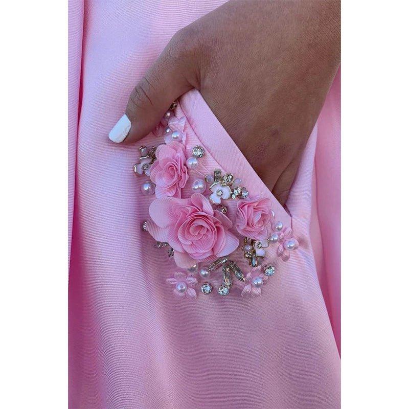 Vestido largo de fiesta rosa satinado de corte evasé con tirantes finos, escote redondo y bolsillos. 
