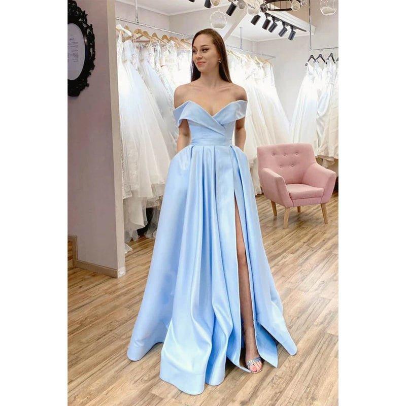 Vestido largo de fiesta de corte A, color azul celeste satinado, con hombros descubiertos, abertura alta y bolsillos. 