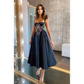 Vestido de fiesta negro de corte A con escote corazón y apliques, largo hasta la rodilla.