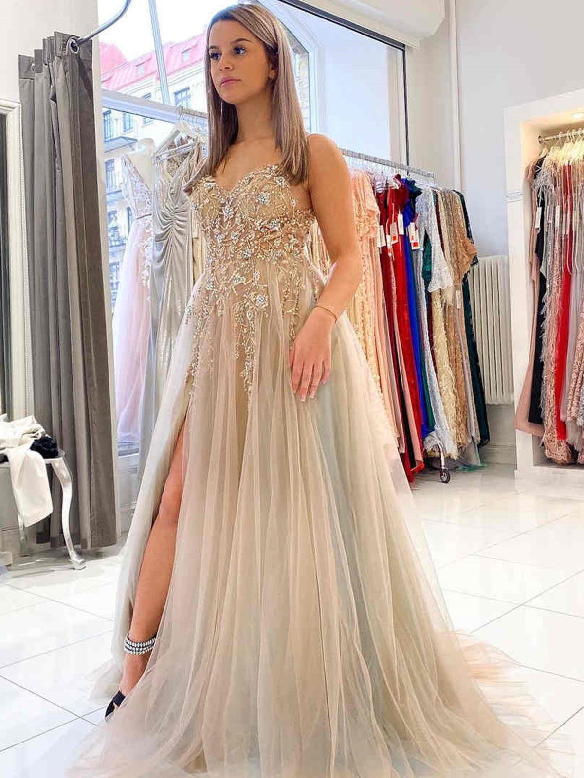 Vestido largo de fiesta gris de corte evasé, con escote en V, espalda descubierta, tul y cuentas, con abertura alta.