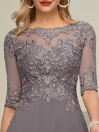 Robe de mère de la mariée asymétrique en mousseline de soie et dentelle, coupe trapèze, col bateau illusion, ornée de sequins et de perles.