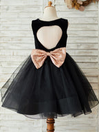 Vestido negro de terciopelo con lazo de lentejuelas en forma de corazón en la espalda y largo hasta la rodilla 
