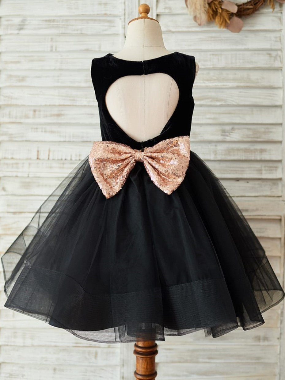 Vestido negro de terciopelo con lazo de lentejuelas en forma de corazón en la espalda y largo hasta la rodilla 