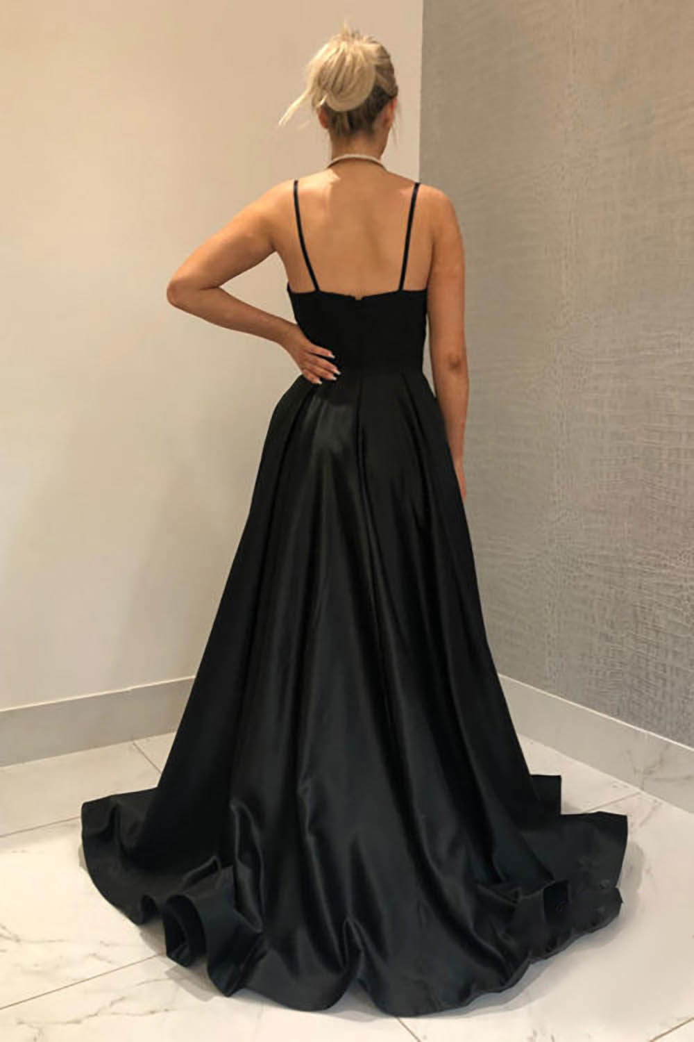 Vestido largo de fiesta negro de corte A con tirantes finos y falda asimétrica.