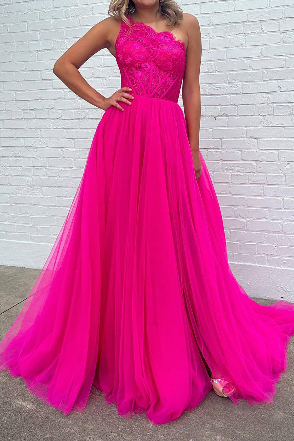 Vestido de fiesta fucsia de corte A, corte asimétrico, con corsé y abertura frontal.