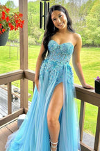 Vestido de graduación azul con corsé, escote corazón y apliques, corte en A y abertura frontal.