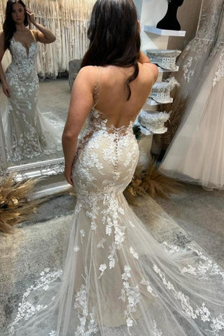 Magnifique robe de mariée ivoire sans manches, en tulle et dentelle, à fines bretelles spaghetti et ornée d'appliqués.