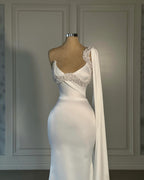 Impresionante vestido de novia blanco de sirena, de satén, sin mangas y con un solo hombro, adornado con pedrería.
