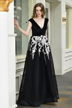 Atractivo vestido de fiesta negro de corte A con escote en V y apliques florales blancos de tul.
