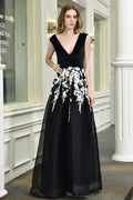 Atractivo vestido de fiesta negro de corte A con escote en V y apliques florales blancos de tul.