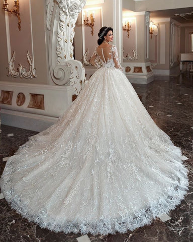 Robe de mariée longue trapèze à manches, ornée de perles et d'appliques en dentelle, avec traîne et manches.