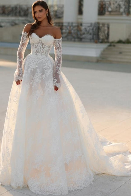 Robe de mariée blanche longue en dentelle, coupe trapèze, épaules dénudées et manches longues, ravissante.